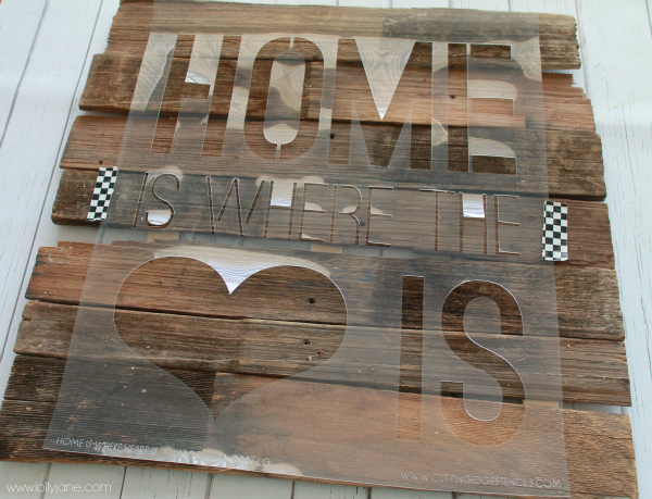 Lay stencil across wood, tape down to create Home is Where the Heart is sign #diy #palletart