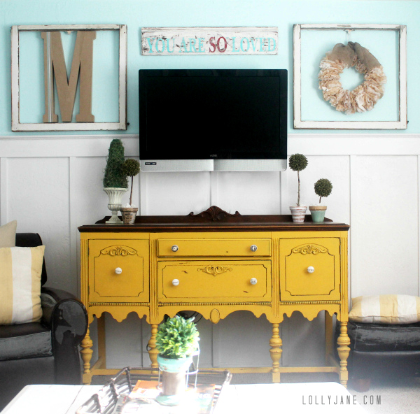 How to decorate around a tv, place frames around tv and a small sign above it to balance it out.