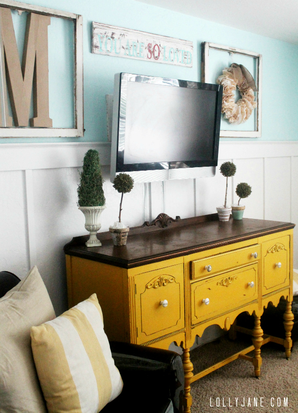 How to decorate around a tv, place frames around tv and a small sign above it to balance it out.