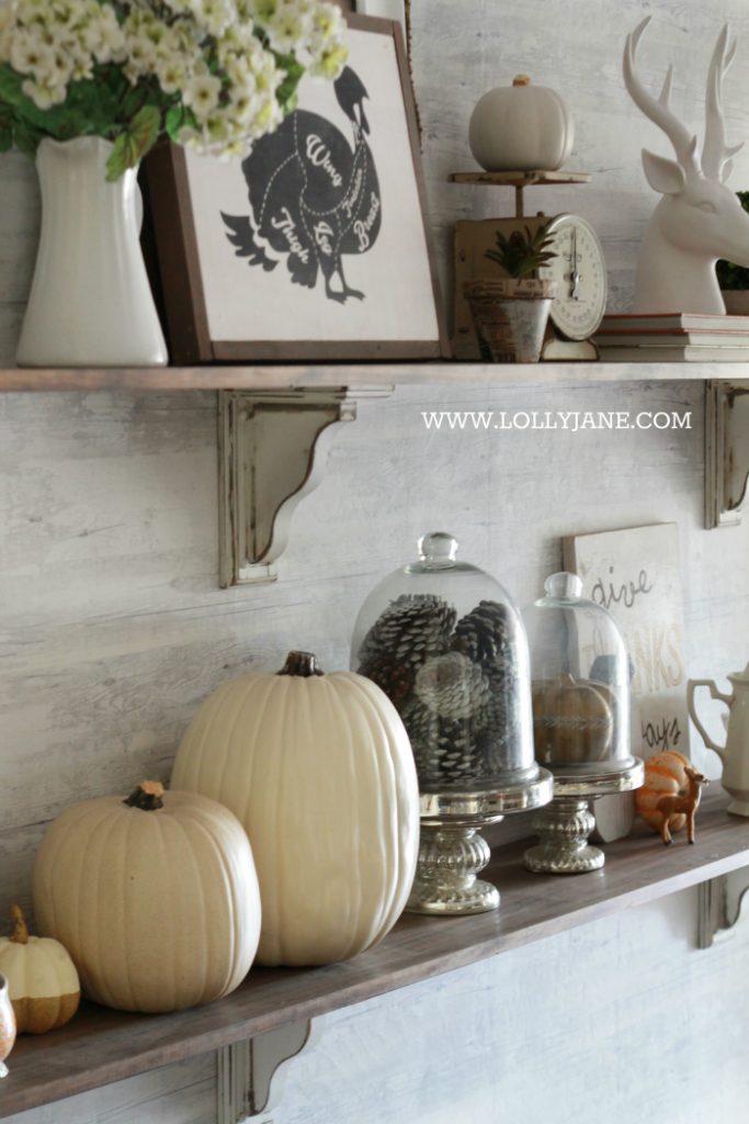 Beautiful farmhouse Thanksgiving dining room decorations. Decorate the table and shelves in layers of pumpkins and signs, fill in with greenery, books and pinecones. Cute Thanksgiving decor ideas that you can easily copy!