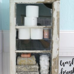 DIY Bathroom Cabinet - How to install a bathroom cabinet on the wall. We used an old trunk insert and a vintage window to create a chippy but sturdy bathroom cabinet. Love this farmhouse bathroom! Such a fun bathroom cabinet diy!