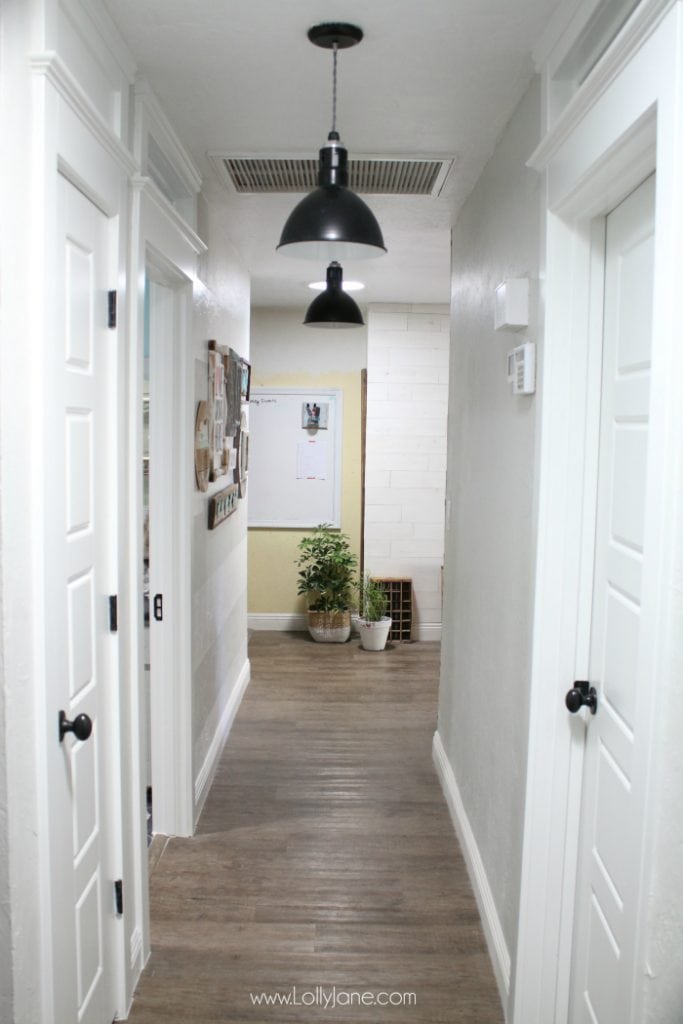 Love this farmhouse hallway makeover. The raised ceilings, black barn light pendants and transom windows add so much character to this old house makeover.