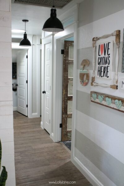 Farmhouse hallyway makeover: love these five panel doors, stripe hallway gallery wall, pendant lighting and an old chippy door for the bathroom!