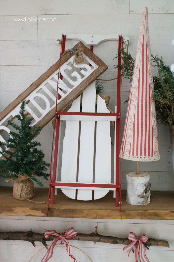 Loving this sled mantel Christmas decor ideas. Use a sled as a focal point for an easy Christmas mantel idea, fill it with a sign, fresh greens in a bucket and small pine trees!