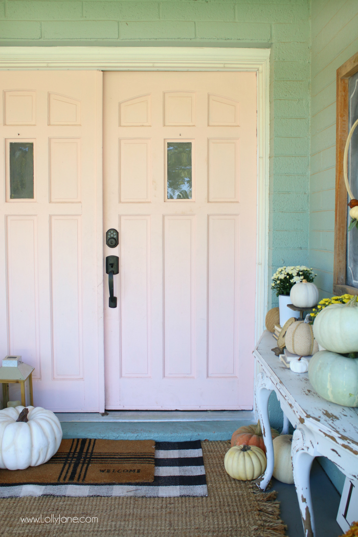 Loving these pink doors and subtle fall decor with fresh white pumpkins and aqua gourds. How to decorate your porch cute for fall! #falldecor #falldecorating #fallporchdecor #outdoordecor