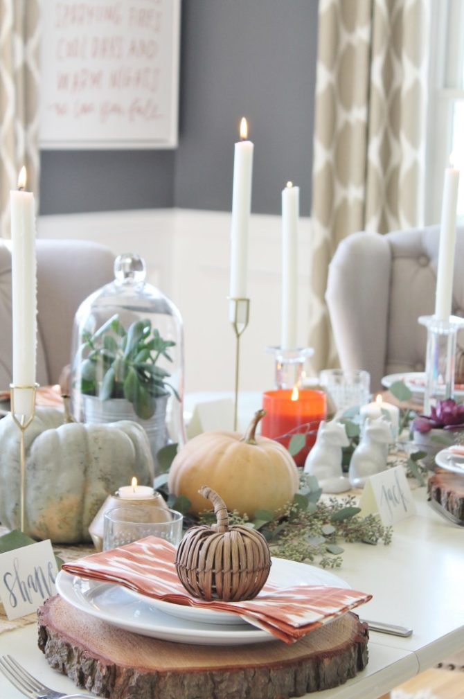 Love these Thanksgiving table decorations, so pretty! Stack neutral plates on a wood charger and fill the table with glasses and candles for an easy to decorate Thanksgiving party setting. #thanksgiving #thanksgivingdecor #thanksgivingtable