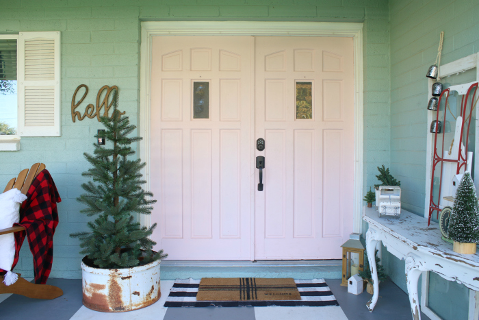 Simple Christmas porch decor on my blue house with pink doors! Looking for easy ways to decorate your porch for Christmas? We've got lots of ideas from several bloggers! #christmashometour #christmasporchideas #christmasdecorations