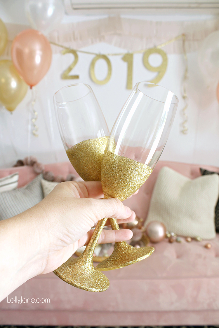 Easy DIY New Years Eve decor! If you can't find these in-store, just spray adhesive on champagne glass + roll in glitter. PERFECT to toast into the New Year! #nye #newyearseve #nyeparty #diy