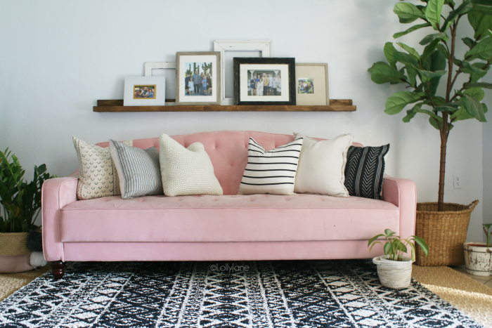 Such fun mid century modern living room furniture! Love this pink velvet tufted couch paired with a tribal rug and plants for pretty boho decor. #eclecticdecor #bohodecor #midcenturymoderndecor