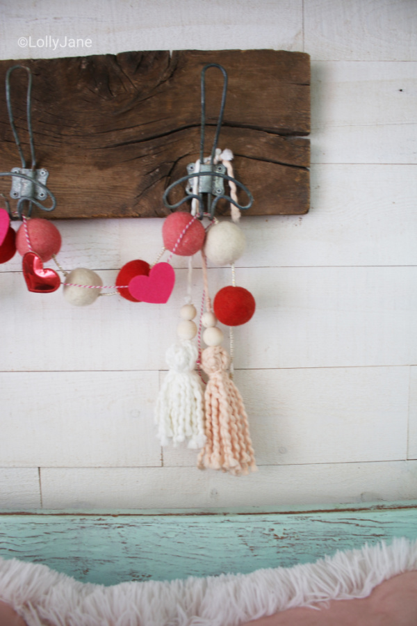 Such a cute yarn home decor neutral tassel for Valentine's Day! Love this pretty soft pink yarn tassel, the cutest Valentine's Day garland! #vintagevalentinesday #valentinesdaydecor #vdaydecor #vdaymantel #valentinesdaymantel #bluemasonjarcollection #pinkvaletinesdaydecor #pinkyarntassel #woodbeadtassel #valentinesdaygarland