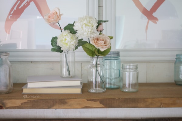 Love these simple mason jar flower arrangements using recycled glass jars and filled with carnations and pink roses. The perfect Valentines Day mantel decor, so easy to put together. #vintagevalentinesday #valentinesdaydecor #vdaydecor #vdaymantel #valentinesdaymantel #bluemasonjarcollection #pinkvaletinesdaydecor #masonjarflowerarrangement #masonjarflowers