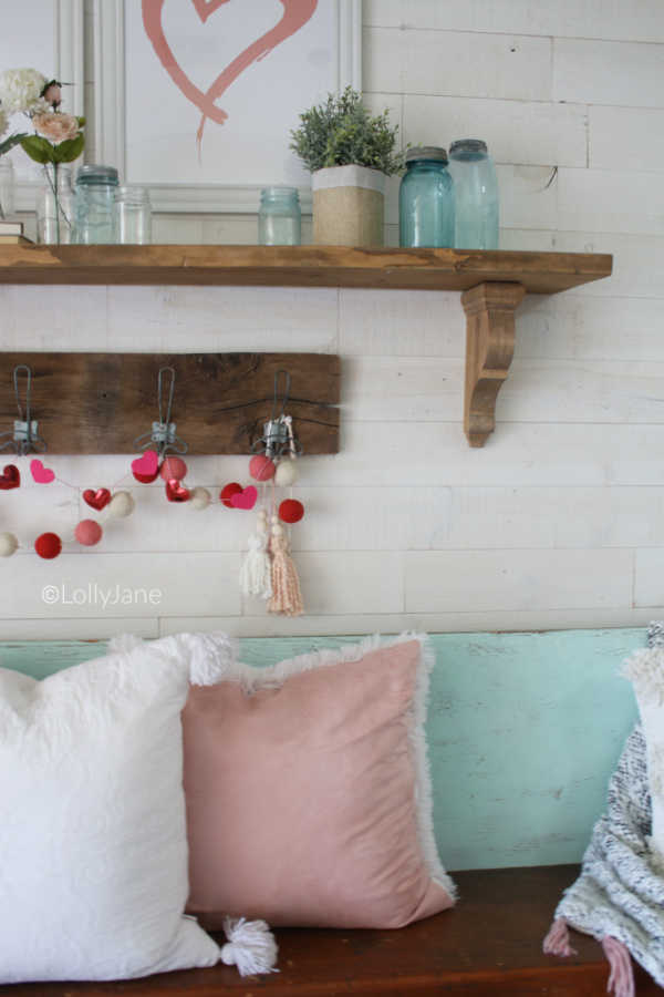 Valentines Day entryway decor ideas. Such a fun Valentines Day mantel using glass jars and flowers and greenery to brighten up your Valentines Day mantel! #vintagevalentinesday #valentinesdaydecor #vdaydecor #vdaymantel #valentinesdaymantel #bluemasonjarcollection #pinkvaletinesdaydecor #masonjarflowerarrangement #masonjarflowers