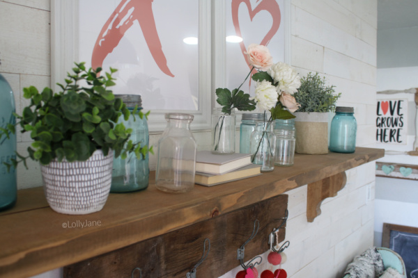 Easy Valentines Day mantel decor ideas | Use these easy to implement decor ideas to put together a simple Valentines Day mantel using aqua jars and pink flowers. #vintagevalentinesday #valentinesdaydecor #vdaydecor #vdaymantel #valentinesdaymantel #bluemasonjarcollection #pinkvaletinesdaydecor #masonjarflowerarrangement #masonjarflowers