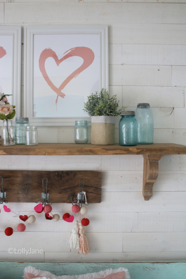 Valentines Day Mantel Decorations | Check out this easy VDay mantel decor using old jars and flowers with a cute pom pom garland and yarn bead tassel! #vintagevalentinesday #valentinesdaydecor #vdaydecor #vdaymantel #valentinesdaymantel #bluemasonjarcollection #pinkvaletinesdaydecor #masonjarflowerarrangement #masonjarflowers