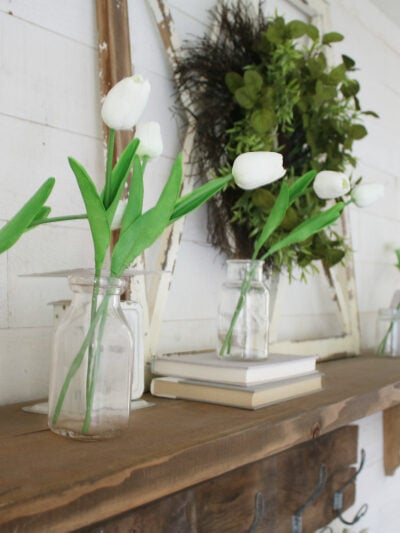 Love these artificial tulips to create easy spring mantle decorations. Adore the old window with a green wreath and old books. #easydecor #springmantel #tulips #decoratingwithtulips #springdecorations
