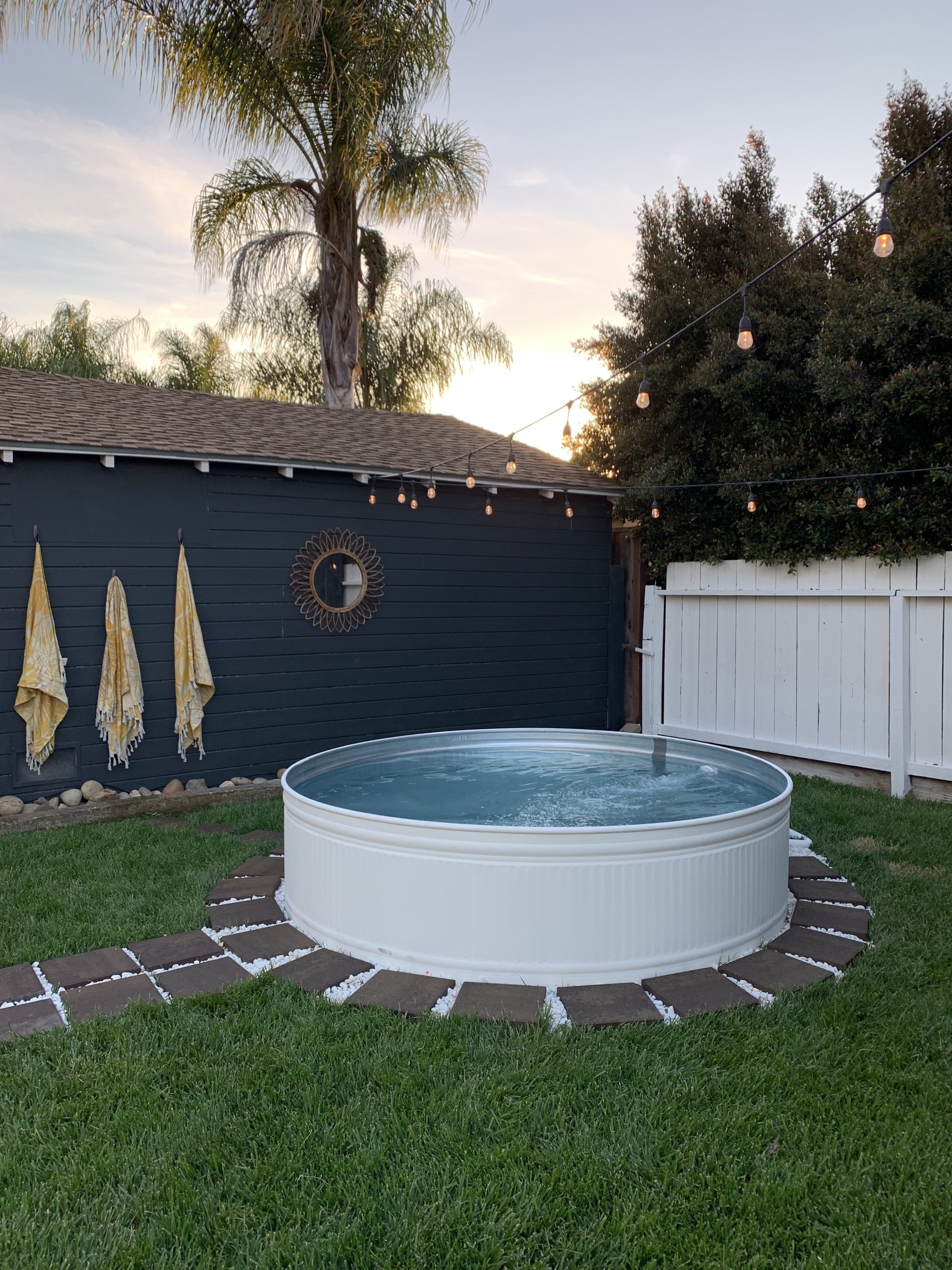 This diy stock tank pool painted white is the first one we saw. She painted it from galvanized metal to white with your everyday outdoor exterior paint. We love that it matches her cute home perfectly! And can we talk about the rocks and stone around the pool? Really dresses it up! #stocktankpooldiy #diypool #diystocktankpool #outdoorpool #diyswimmingpool #outdoordecor