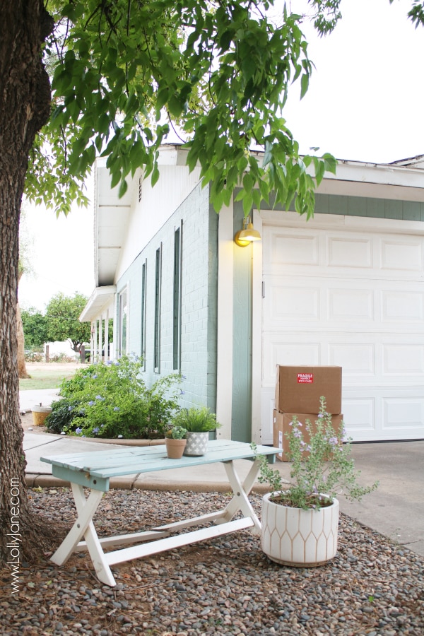 Looking for blue farmhouse exterior ideas? We love our colorful blue brick house with cheery yellow farmhouse lights on the paneled garage. #farmhouse #farmhousestyle #barnlights #yellowlights #homedepot