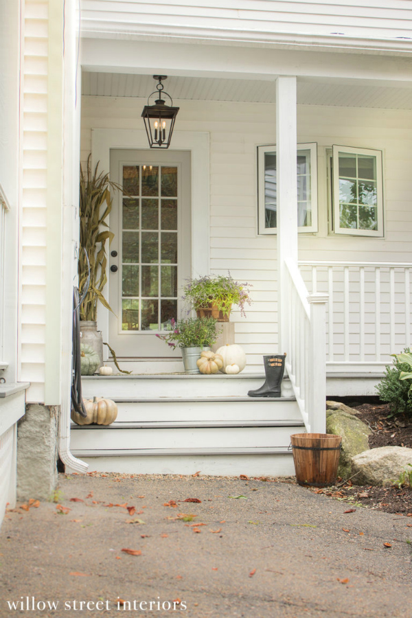 Such a pretty fall front porch with flowers, green and white pumpkins, all placed in an assortment of planters. #fallfrontporch #porchfalldecor #falldecorationsoutdoor #falloutdoordecorations