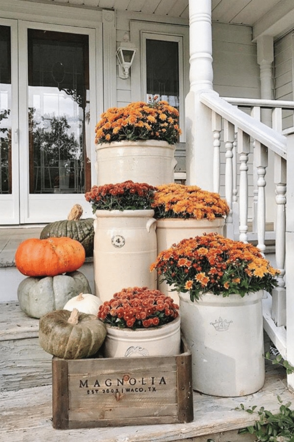 Darling farmhouse fall porch inspiration: mums in crocks and a wood crate to create cozy front porch fall decor ideas. #falldecor #frontporchdecor #howtodecoratewithmumsforfall