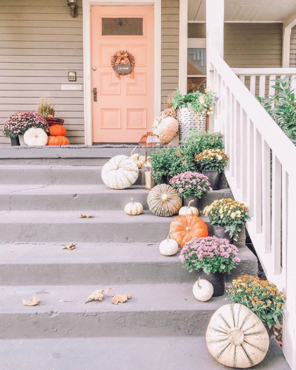 Dying over this pink front porch full of pumpkin decorating ideas! Love the layered pumpkins and mums on this happy fall porch! #fallporch #frontporch #pumpkindecorating