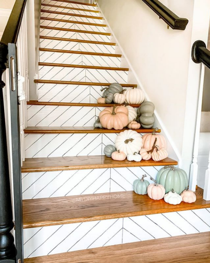 Love these herringbone stairs decorated with muted pumpkins for easy indoor fall decor from . Create this stunning indoor fall decor on your stairs by adding piles of painted pumpkins. SO pretty! #falldecor #paintedpumpkins #decoratedstairs #decoratedstairsfalldecor #herringbonestairs