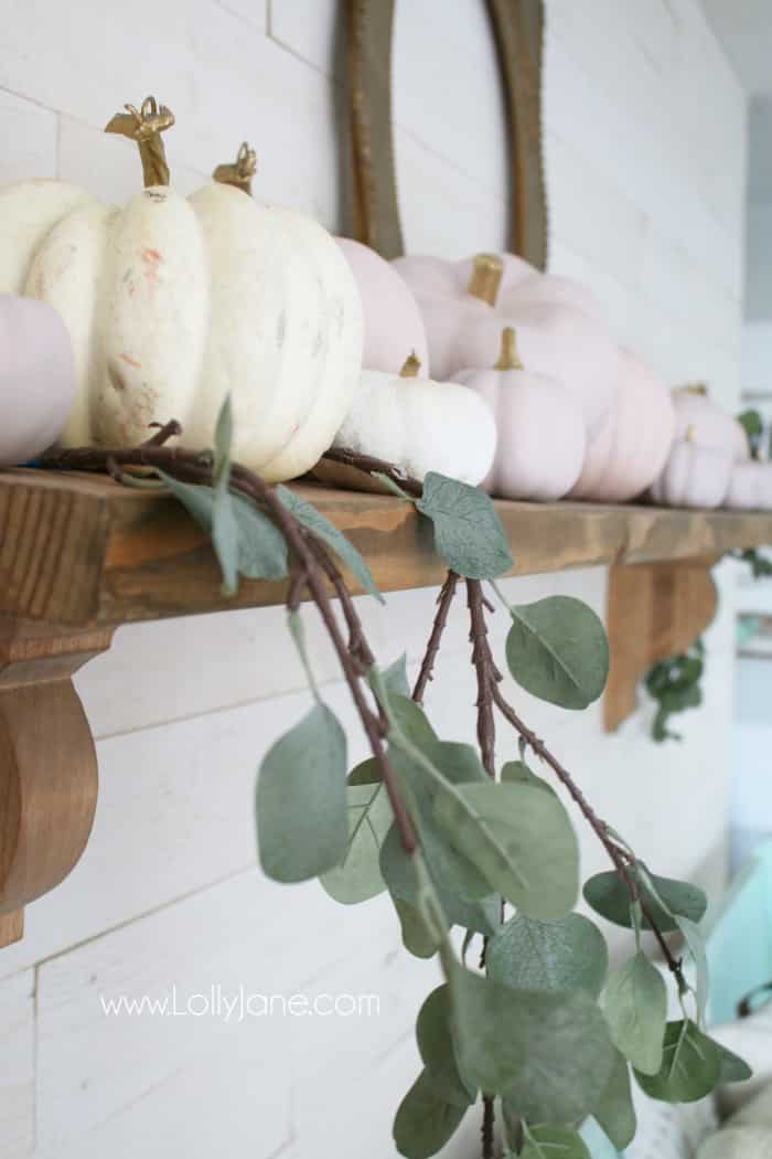 Forget traditional fall colors: try your hand with DIY pink pumpkins for a fresh fall mantel decor this year! Create this look with a little chalk paint and faux eucalyptus leaves to welcome this fall season. #pinkpumpkins #chalkpumpkins #diypumpkins #fallmantel #falldecor #pinkfalldecor