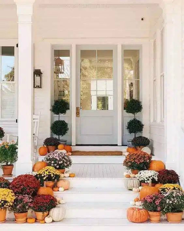 Love the simple pumpkins and mums on the pots for gorgeous front porch fall decor! #pumpkinsmums #fallfrontporchdecor #decoratingstairswithpumpkins #pumpkinsstairsfalldecor