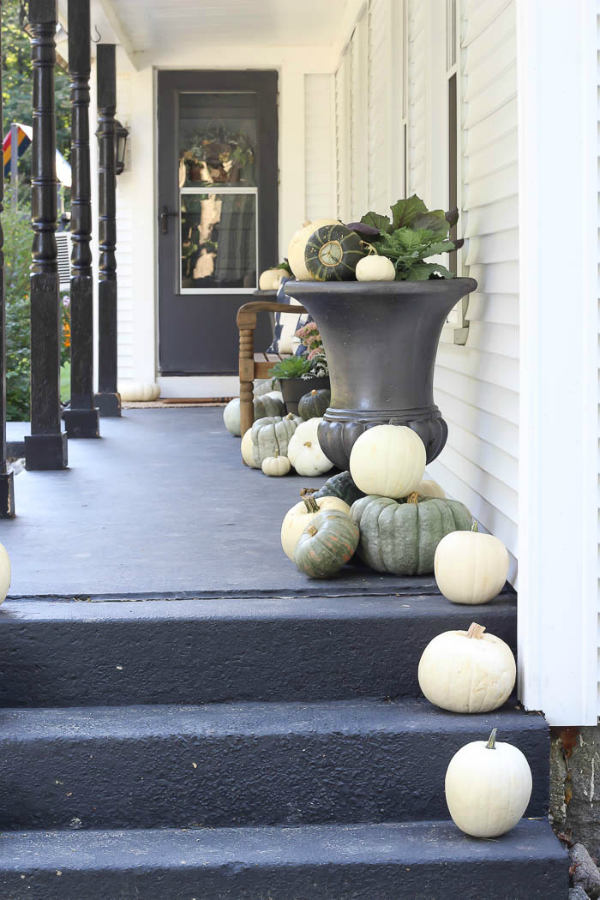 Love this moody dark fall porch decor with white and Cinderella blue pumpkins and squash. #fallporch #fallporchdecorations #fallporchdecor #outdoorfalldecor