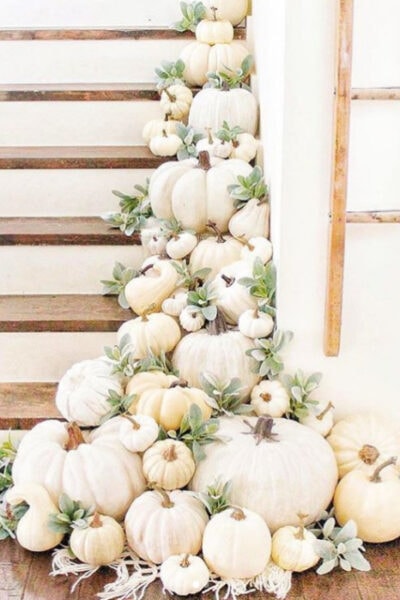 Lay white pumpkins with greenery for easy decorating on stairs. Love this pretty fall decor! #whitepumpkinsgreenery #decoratingstairsforfall #fallstairsdecorating #falldecoratingideas