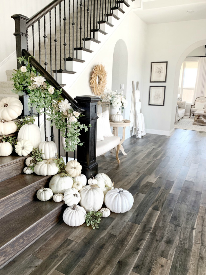 Place white pumpkins down a stairway for easy fall decorations that create a stunning look! Adore this charming fall decor with loads of pumpkins and a pretty garland! #whitepumpkins #pumpkinideas #pumpkinstairway #stairsonpumpkins #decoratingstairsforfall