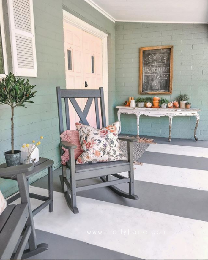 Such fun pink front doors on a blue house! Love this farmhouse porch with gray and white painted porch stripes! #farmhousestyle #farmhousehouse #diypaintedporch #pinkexteriordoors #pinkfrontexteriordoors #pinkpainteddoors