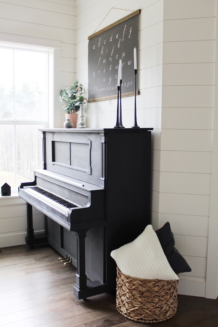 Every house needs a statement piece and this classic black piano would look great in any home! Loving this black painted piano against a shiplap wall, perfect farmhouse charm. #blackpiano #paintedblackpiano #blackpaintedpiano #farmhousepiano