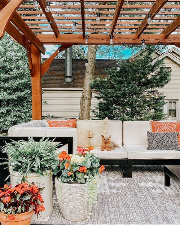 We love this gorgeous patio with its wood pergola, modern farmhouse patio furniture and colorful flower pots and topped it off with the cutest outdoor farmhouse style rug. #modernfarmhouserug #farmhouserug #outdoorrugideas #outdoorrugdecor