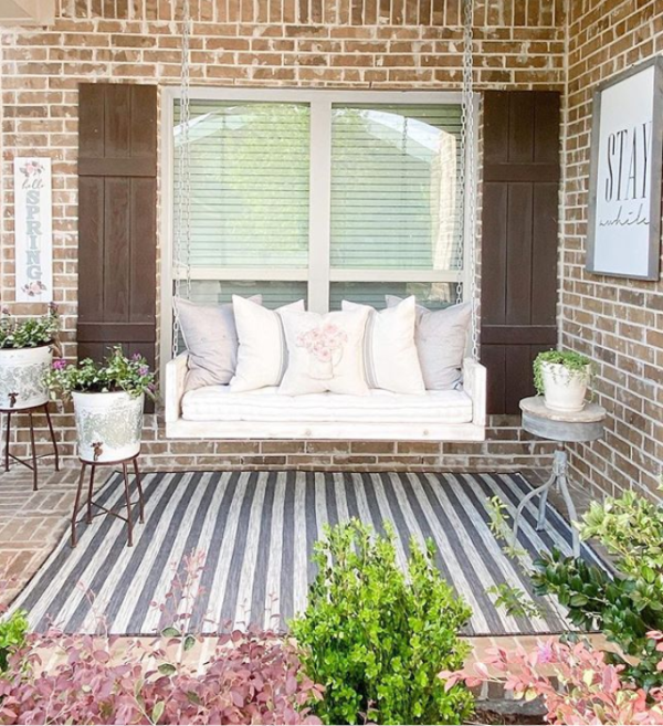 Such a pretty stripe outdoor rug for this cozy farmhouse porch. #stripeoutdoorrug #graywhitestripedrug #farmhouserug #outdoorrugideas #farmhouseporch #farmhouseporchswing