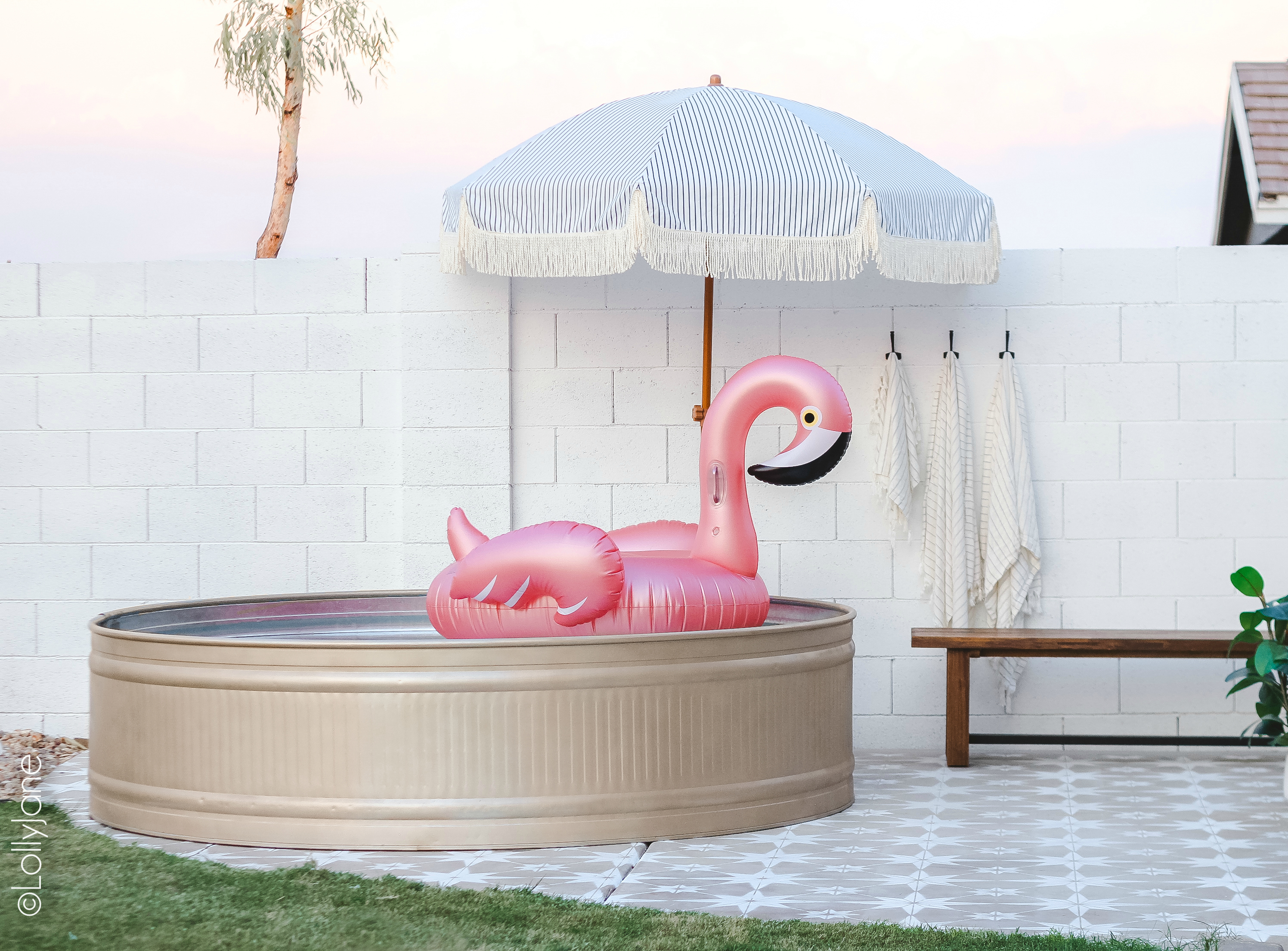 Forget an inflatable pool, spruce up a standard stock tank pool with a few cans of spray paint and elbow grease! So cute. the perfect pool for adults and kids alike! #stocktank #paintedstocktank #stocktankpool #paintedproject #diy