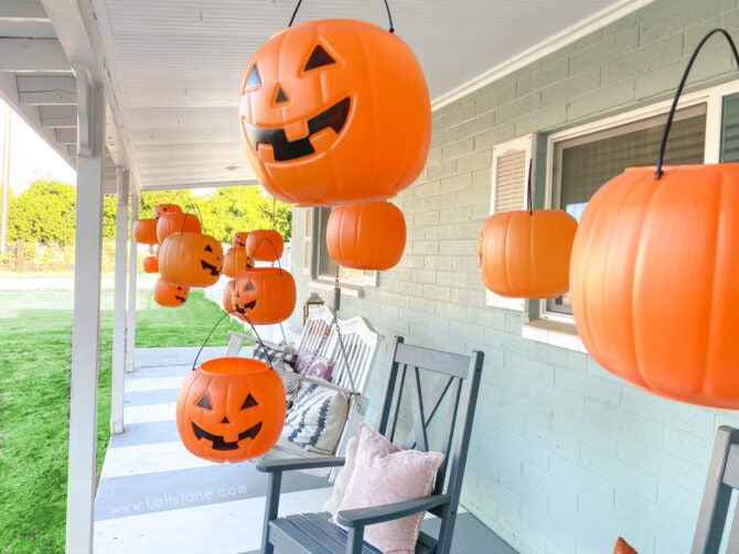 Have you seen those dollar pumpkins around? Turn those cheap plastic pumpkins into hanging porch decorations. Level up by adding remote control tea lights so they light up at night! #plasticpumpkincraft #dollarstorepumpkins #halloweendecor #halloweendecorations #candypumpkinbucketcrafts #pumpkinbucketdecor #halloweenporchdecor #plasticpumpkindecoratingideas #hangingpumpkinsonporch #hangingpumpkinbaskets