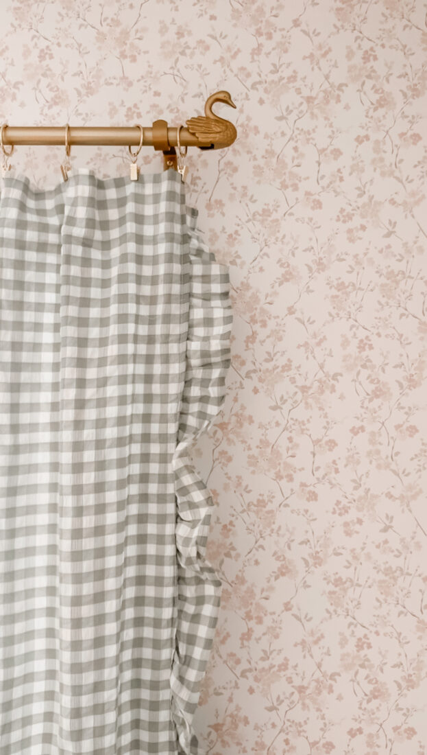 Soft gingham curtains hanging in a cozy cottage-style guest bedroom with floral decor and warm neutral accents