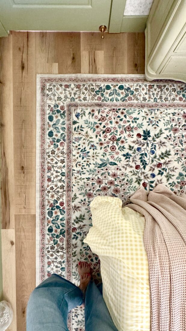 Large neutral washable area rug in a cozy cottage-style guest bedroom with floral bedding and vintage-inspired decor